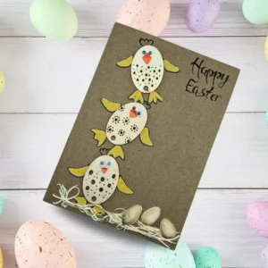 Adorable Handmade Happy Easter Chick Card ‘Celebrate Together’ A handmade happy Easter chick card featuring three wooden chicks with orange wings, accompanied by pistachio shell eggs.
