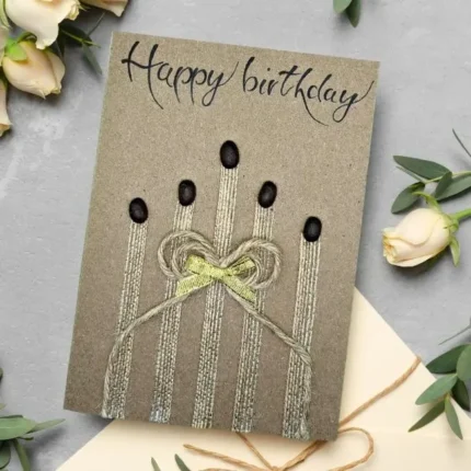 Bespoke and Personalised Handmade Card: Charm of Birthday Candles. Made of Coffee beans, cotton string on brown paper with gold bow.