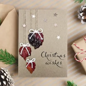 Best Eco-Friendly Christmas Card for with dried leaves and bows hanging from a rope. A simple but beautiful card that is sure to impress.