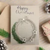 Handmade Merry Christmas card on the beige envelope, showcasing a circle wreath with silver stars accents.