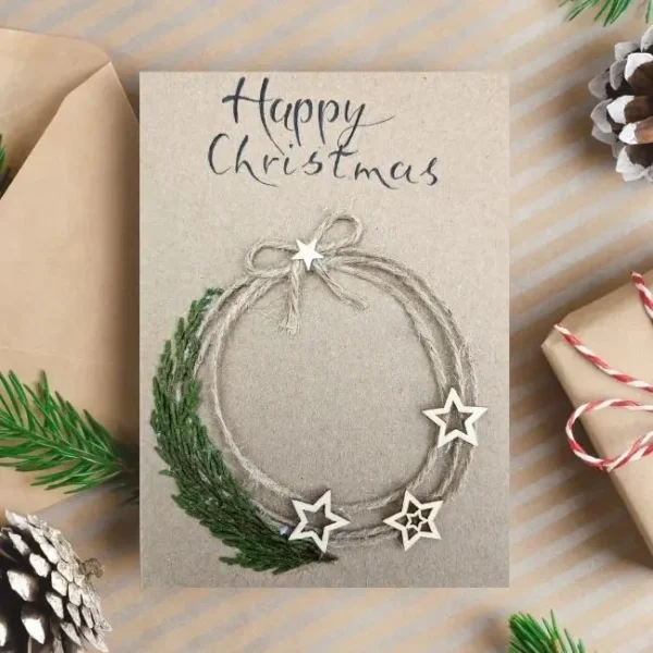 Handmade Merry Christmas card on the beige envelope, showcasing a circle wreath with silver stars accents.