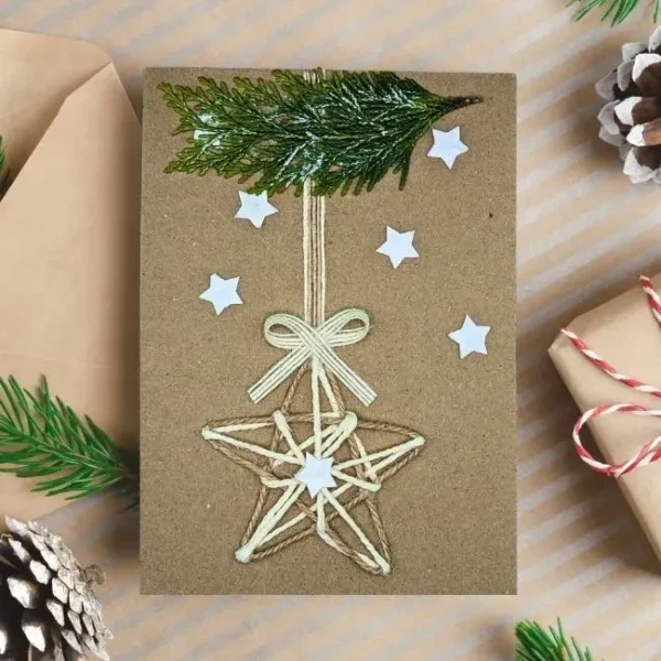 Handmade Rustic Christmas card with a yarn star, Christmas tree branch, and white stars.