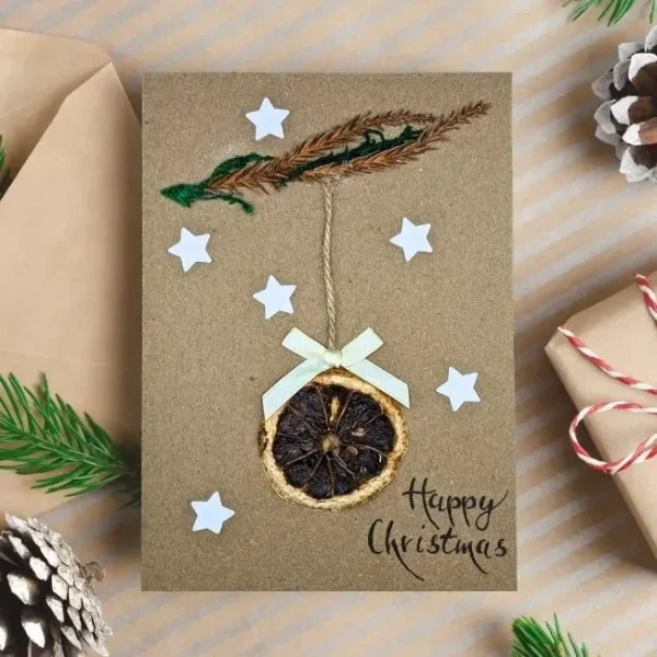 Handmade Personalised Christmas card featuring a dried orange slice, white stars, and a bow.