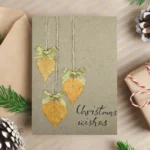 Best Rustic Handcrafted Christmas Card made in the UK with dried leaves, gold bows and the text 'Christmas wishes'.