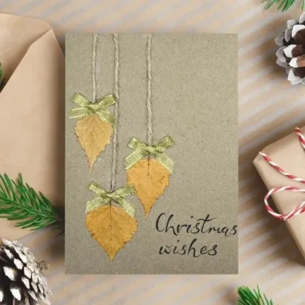 Best Rustic Handcrafted Christmas Card made in the UK with dried leaves, gold bows and the text 'Christmas wishes'.
