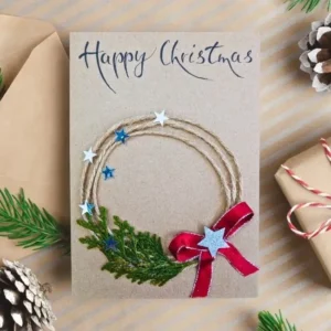 Fabulous Handmade Christmas Card Idea with Festive Wreath image 1 Fabulous handmade Christmas card with festive wreath, star, red ribbon, and text Happy Christmas.