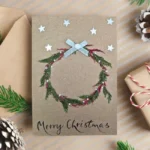 Wreath Christmas Card idea featuring a handmade, embroidered red and green wreath with a silver bow.