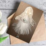Handmade card for new mother with white feathers on a brown reusable envelope.