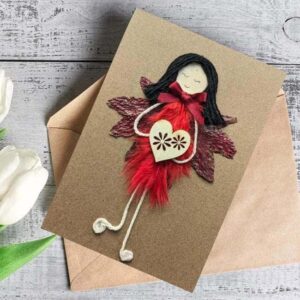 Handmade Personalised Unique Greeting Card for Female Birthday featuring a whimsical women figure with red feathered dress, holding a heart, against a brown envelope.