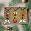 Three reindeer faces on a Hilarious Reindeer Family Holiday Card, surrounded by pine needles, conveying a humorous family theme.