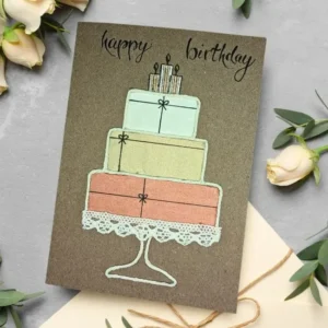 Perfect Handmade Birthday Card featuring a three-tiered cake design with pastel colours and candle decorations, surrounded by pale flowers and an envelope.