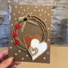 A person holds a perfect handmade Valentine's Day card with colourful hearts and a wreath.