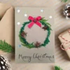 Personalised Handmade Christmas card on brown paper, displaying festive wreath and red ribbon bow.