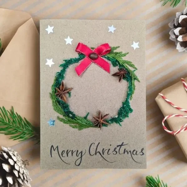 Personalised Handmade Christmas card on brown paper, displaying festive wreath and red ribbon bow.