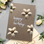 Unique Handmade Pistachio Shell Flower Birthday Card with 4 flowers made of pistachio shells with Happy Birthday text in the middle.