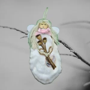 The image displays a unique white shell ornament made from oyster shells. She is holding a bouquet of dried flowers in her hand.