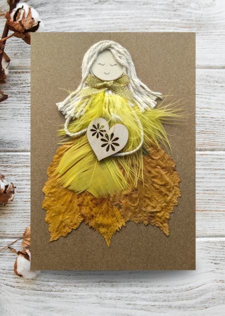 Card displaying a yellow women made of feathers, part of the Handmade Cards for Her collection banner.