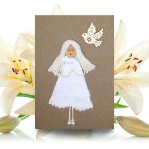 A handmade Communion card depicting a girl in a white dress with a white dove, representing innocence and spirituality.