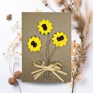 A decorative card with sunflowers and a ribbon, representing the Handmade Flower Cards category.