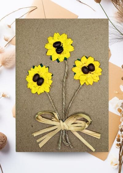 Decorative card featuring sunflowers and coffee beans, adorned with a ribbon, representing Handmade Flower Cards.