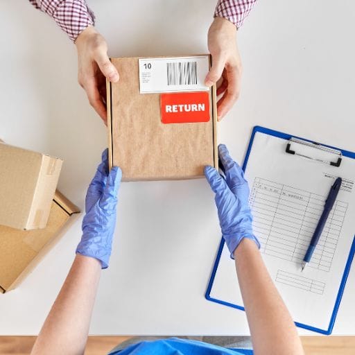 A person holding a labelled box for returns or exchanges from the Heart in Creation website.