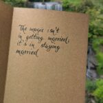 Rustic brown card featuring hand-calligraphy in black ink, showcasing elegant lettering with a scenic outdoor backdrop.