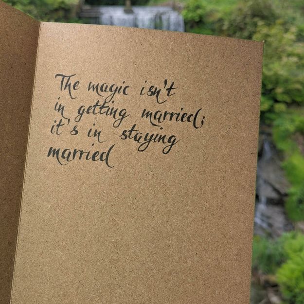 Rustic brown card featuring hand-calligraphy in black ink, showcasing elegant lettering with a scenic outdoor backdrop.