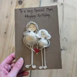 Unique handmade birthday card for mum, featuring seashell and rope mother-daughter figures holding a heart