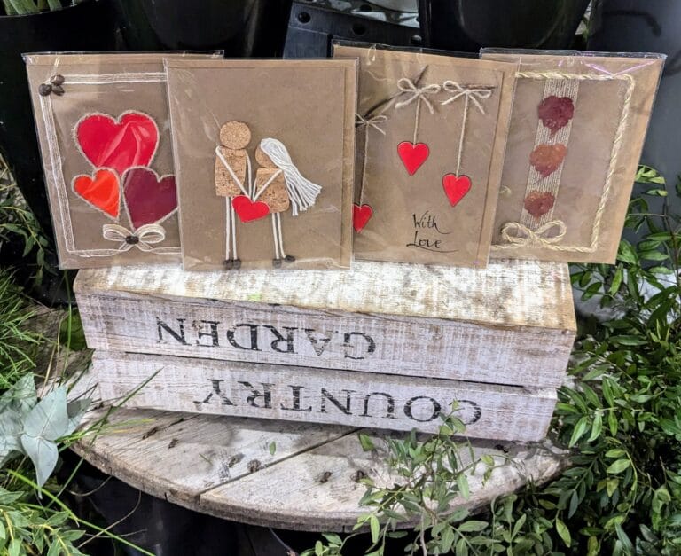 A wooden crate displaying four handmade Valentine cards, featured on the Heart in Creation Contact Us page.