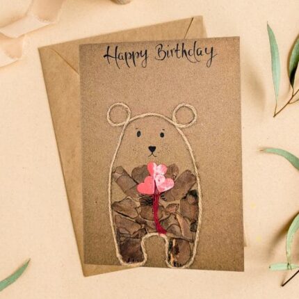 Eco-friendly rustic bear birthday card featuring a cute bear holding hearts, handmade from recycled materials.