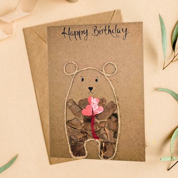 Eco-friendly rustic bear birthday card featuring a cute bear holding hearts, handmade from recycled materials.
