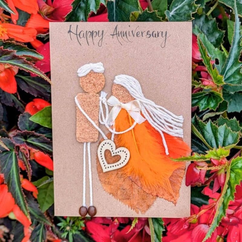 Cork in handmade card featuring an anniversary couple design made from cork, twine, feathers, and a wooden heart detail.