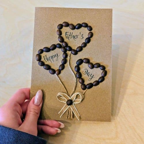 Coffee in handmade cards shown as a handmade Father’s Day card with heart-shaped balloons formed from real coffee beans, tied with string and finished with handwritten calligraphy.