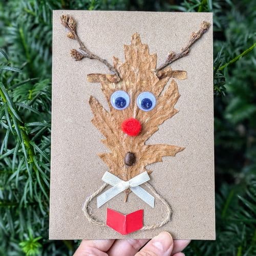 Dry leaves in handmade cards shown as a playful Christmas card featuring a reindeer face made from a natural leaf, twine antlers, and festive details.