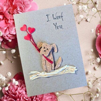 Handmade Dog Mum Valentine's Card featuring a 3D puppy silhouette crafted from natural cork, holding three red paper heart balloons with real red twine on a rustic kraft paper background.