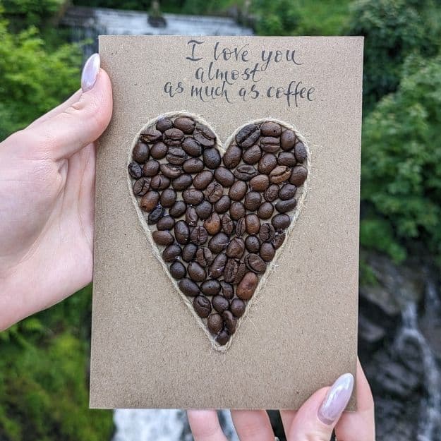 A sentimental kraft card featuring a large heart mosaic made from roasted coffee beans and outlined in twine, showcasing creative luxury handmade card materials for coffee lovers.