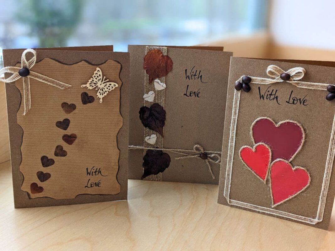 Three romantic handmade Valentine’s cards UK featuring rustic designs with "With Love" text, including heart cards with red paper cutouts, love cards with coffee bean accents, and romantic cards adorned with twine bows and butterfly embellishments.