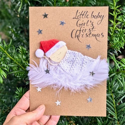 Types of greeting cards – handmade new baby card on kraft paper featuring a sleeping baby with feather details and festive accents.